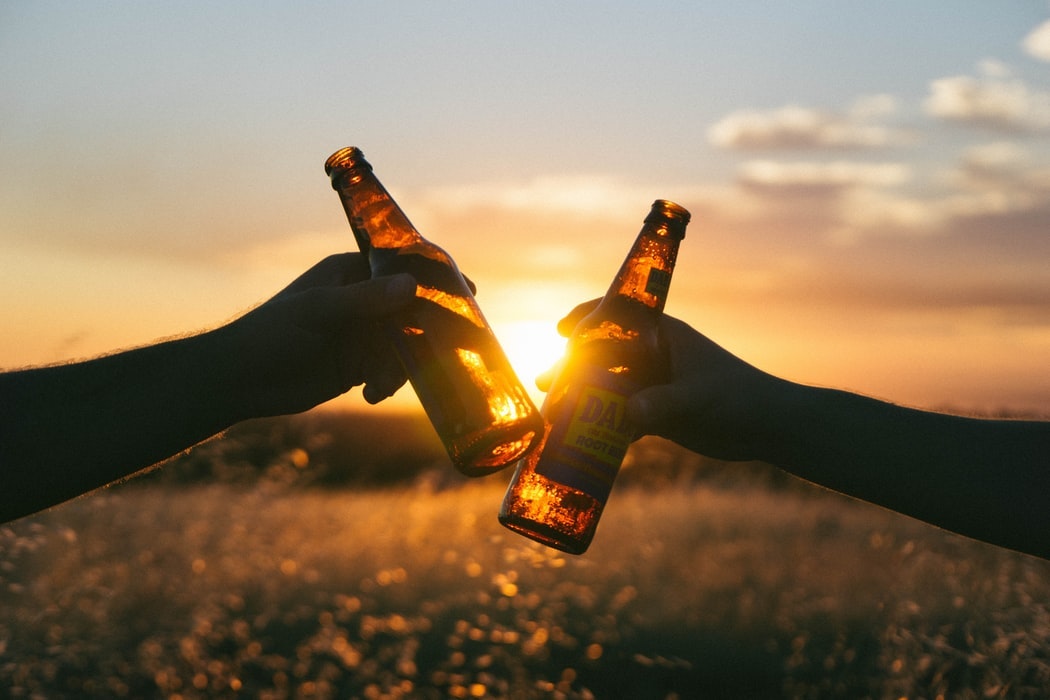 Livraison d'apéro à domicile avec Apéro Minute : deux amis trinquent avec des bières fraîches au coucher du soleil près de Rennes, en Bretagne.